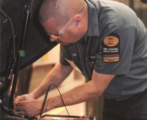 Technician working on battery under forklift hood