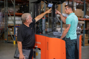 A worker gets forklift safety training in a warehouse.