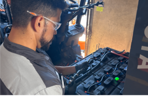 A technician examines a forklift battery.