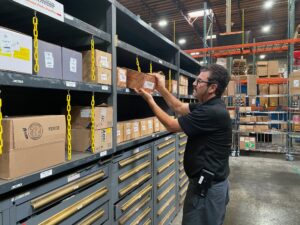 A man places a box of forklift parts on a shelf.