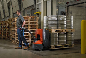 man pulling an electric pallet jack in a warehouse